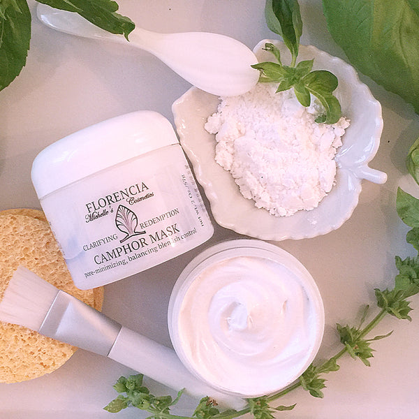 A Camphor Mask Clarifying Redemption container next to a white leaf dish with powder and an open bottle of the mask from above.