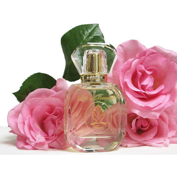 Fleuri Perfume bottle in front of pink roses.