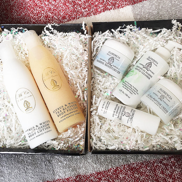 Black gift wrap box opened with two bottles in one box and four bottles in another resting on shredded paper for cushioning.