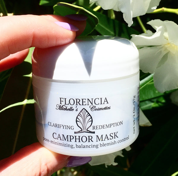 A hand holding a Camphor Mask Clarifying Redemption container.