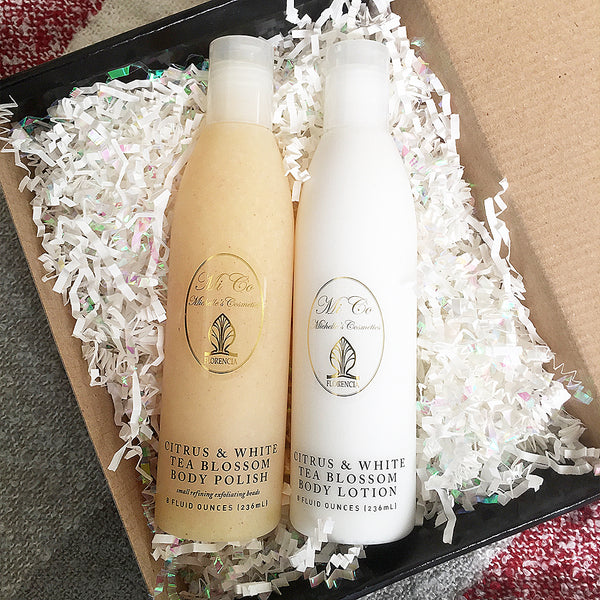 Black gift wrap box opened with two bottles resting on shredded paper for cushioning.