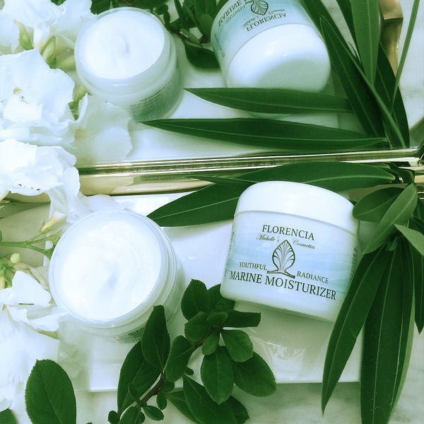Jars of Marine Moisturizer Youthful Radiance reflecting in the mirror with greenery.